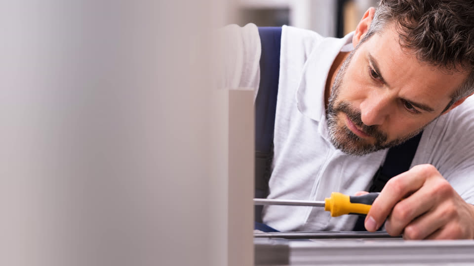 Poseur préparant la pose de portes de cuisine avec un tournevis